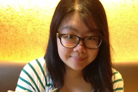 Photo of a student wearing glasses, eating ice cream while smiling at the camera.