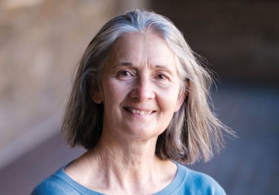 Kathy Tierney stands with arms crossed, smiling, wearing a blue shirt