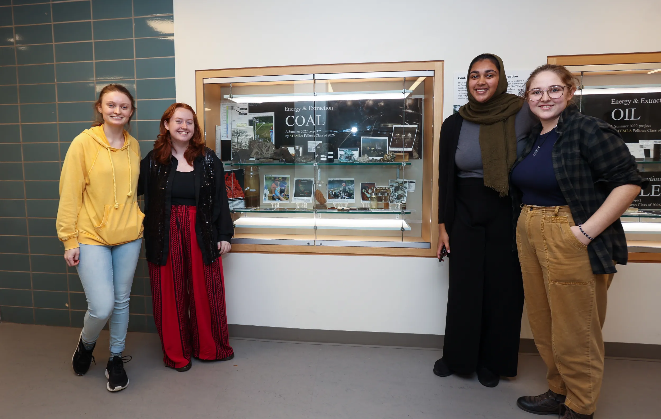 STEMLA Fellows post in front of display case