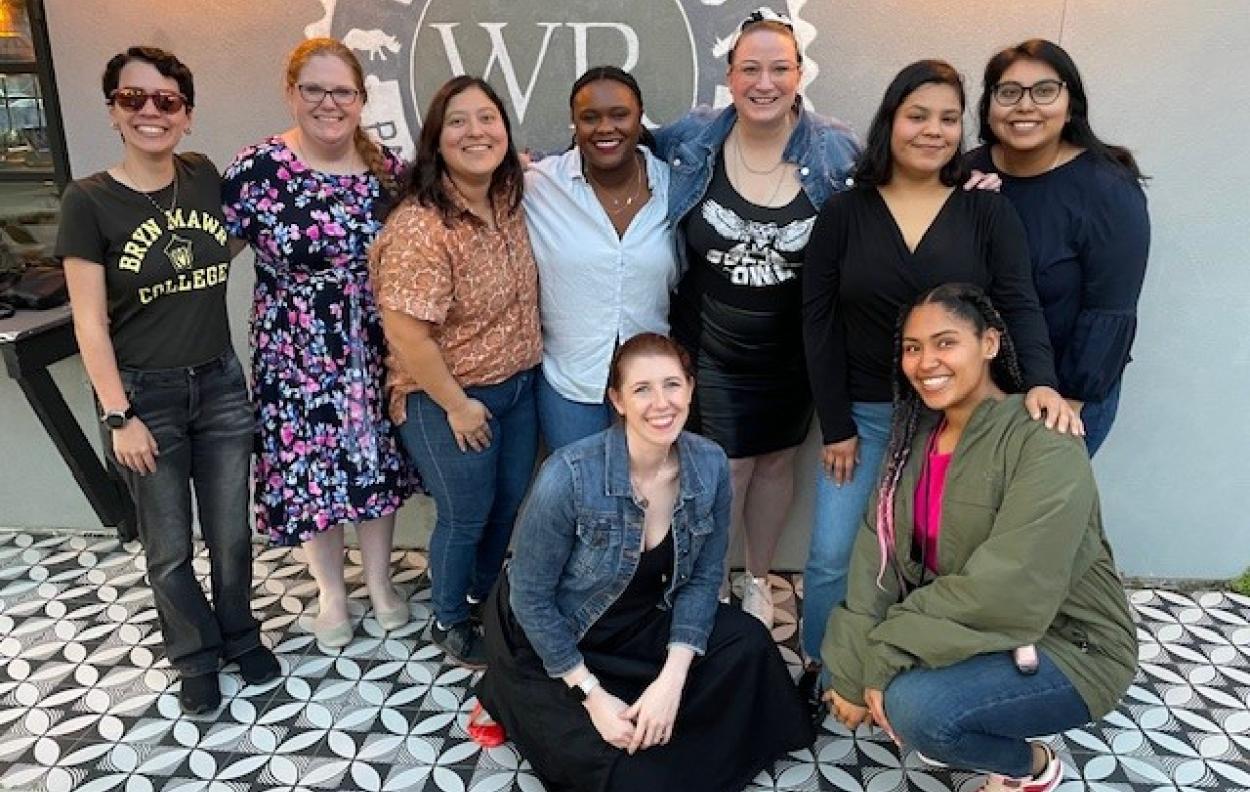 Nine Mawrters smile together inside a bar with a black and white checkered floor.