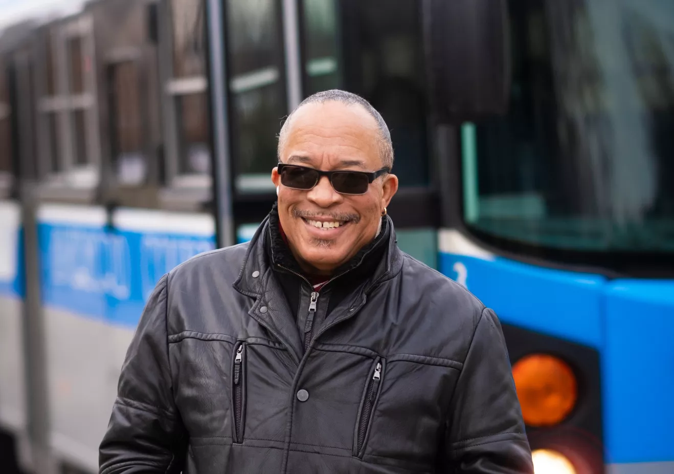 Steve Green smiling and posing in front of the Blue Bus