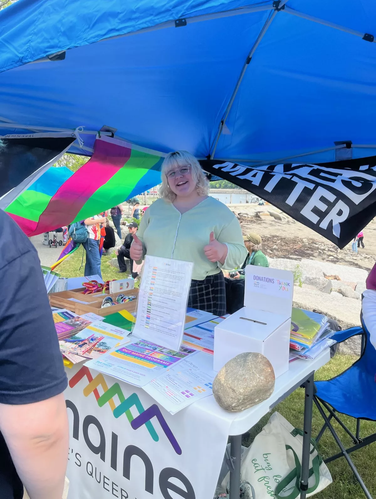 Alex Barstow smiling with thumbs up in front of a table under a tent