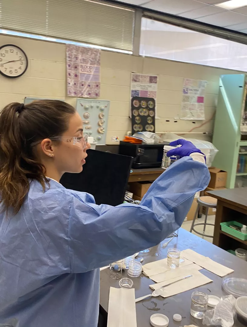 Leila in a lab coat and goggles