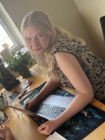 Lillian Ersnt smiling in front of a laptop at a desk. 