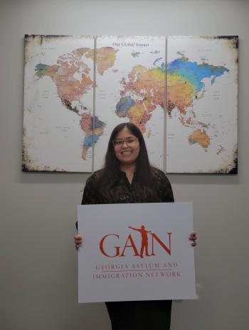 Afiya Khan standing in front of a global map. 