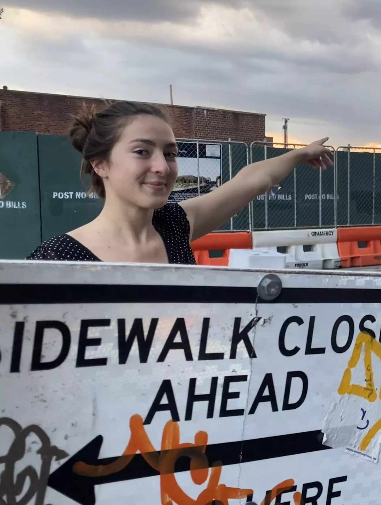 Emma Adelman in front of a sidewalk closed ahead sign. 