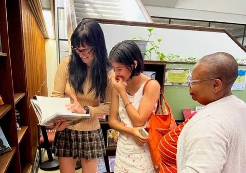 Librarian & students looking at books