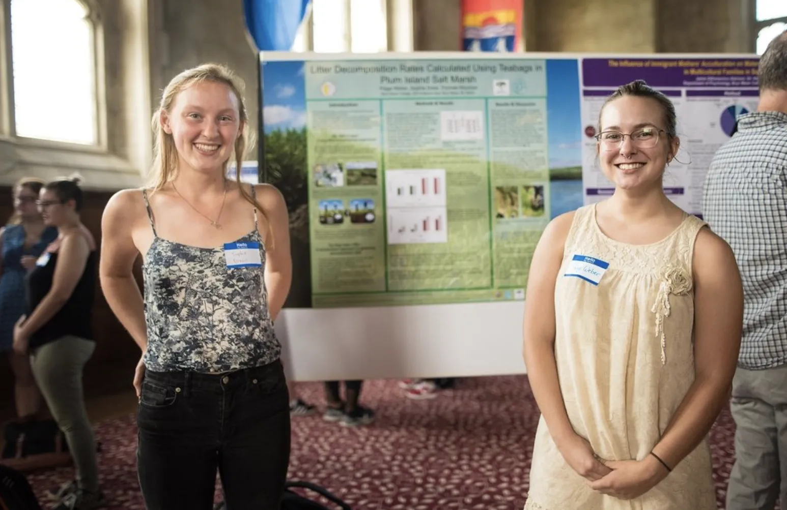 Two students smiling in front of a research poster in the Great Hall