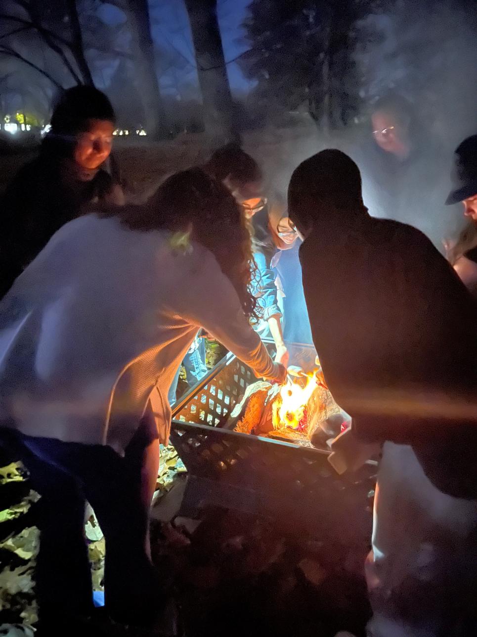 Students roasting marshmallows over the fire pit behind Rhoads dormitory