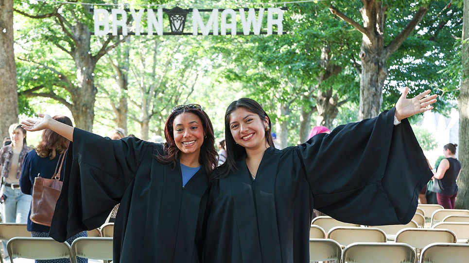 Convocation 2024 two students in front of senior row and Bryn Mawr sign