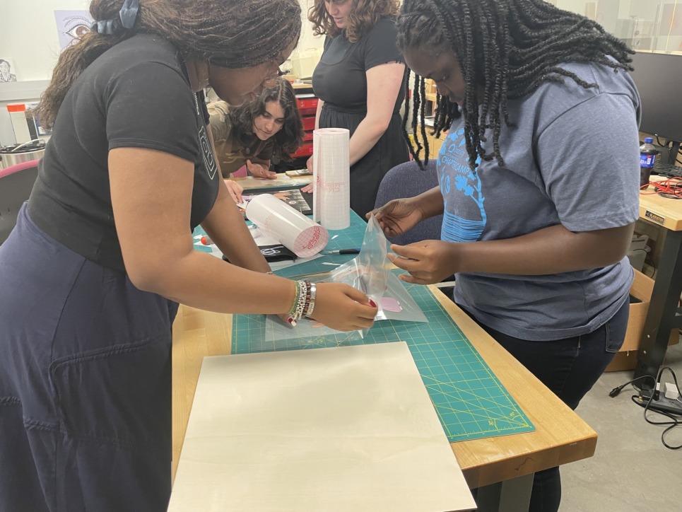 The Digital Technology Interns work with Bronwen Densmore, Makerspace Coordinator, on creating a group tote bag