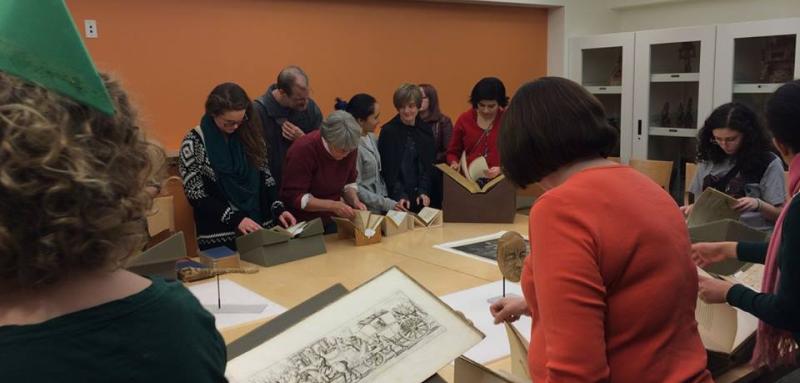 Photo of people in Special Collections Seminar room, looking at rare books.