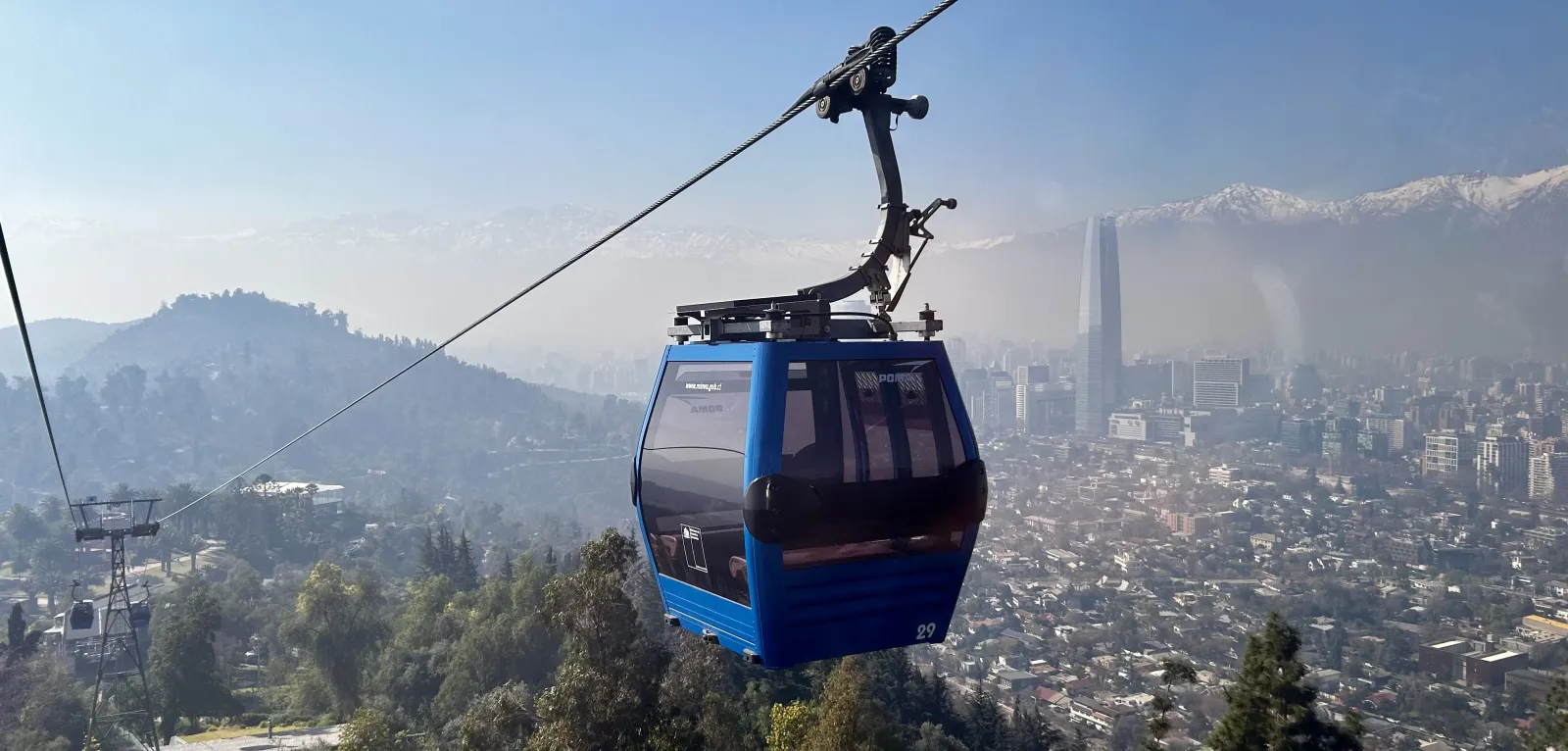 an image of a cable car going up a mountain with a cityscape and mountains behind