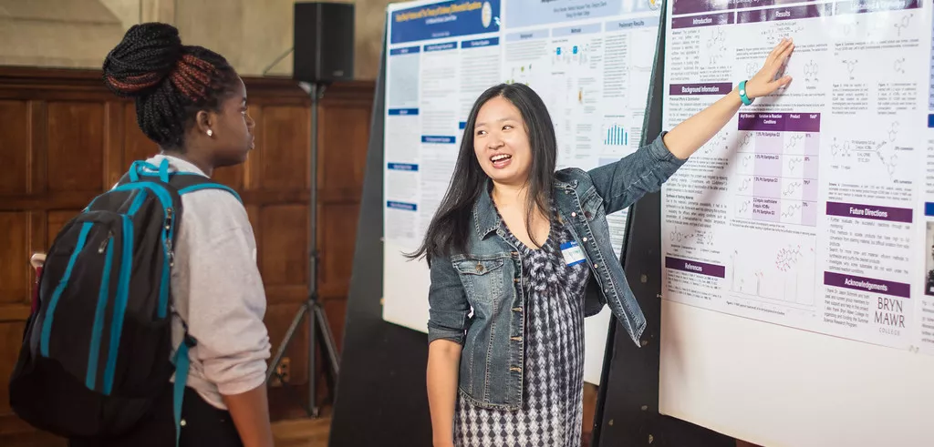 Student shows a poster while another student looks on