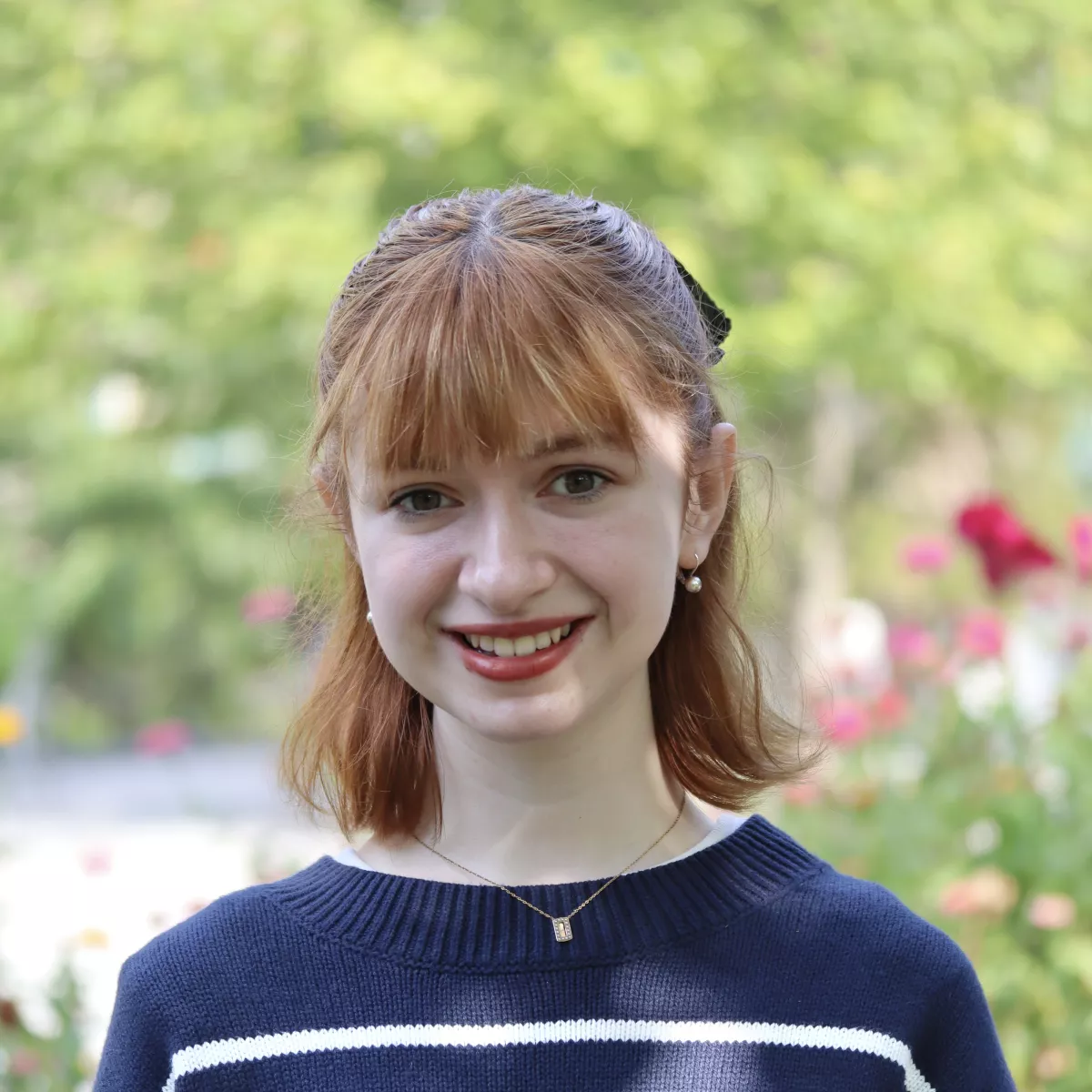 Marie-Claire in a navy sweater with white stripes in front of a landscape