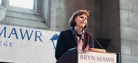 Kim Cassidy standing behind a podium with a Bryn Mawr banner in the background