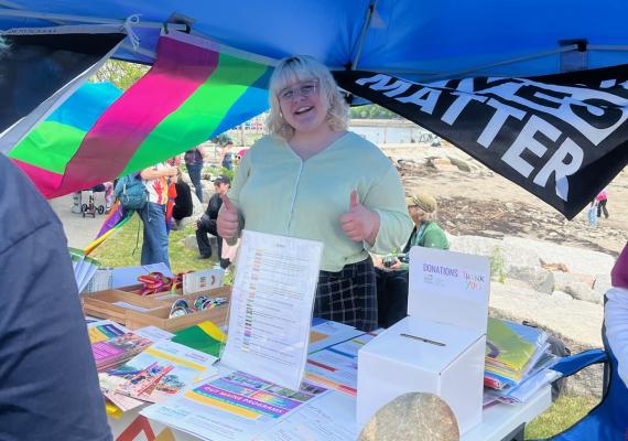 Alex Barstow smiling with thumbs up in front of a table under a tent