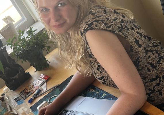 Lillian Ersnt smiling in front of a laptop at a desk. 