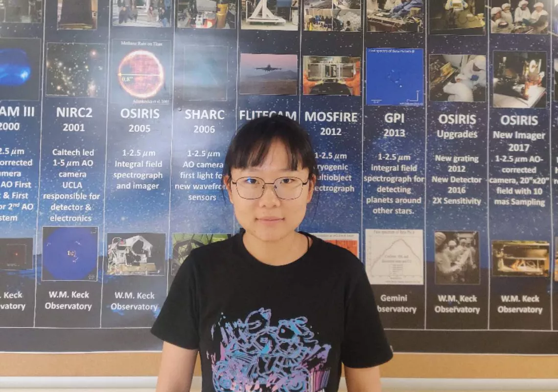 Xiyue Shen standing in front of a UCLA poster.