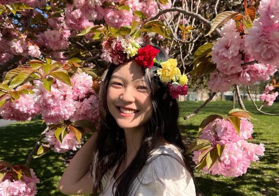 Sharon Liu in front of a cherry blossom tree. 