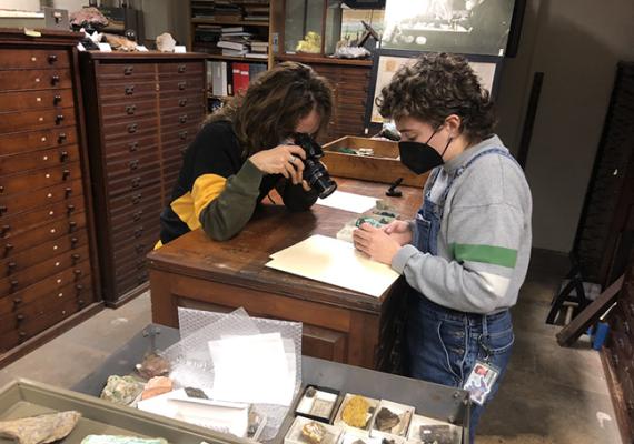 Artist and student look at empty boxes that remain from the uranium once stored in the collection.