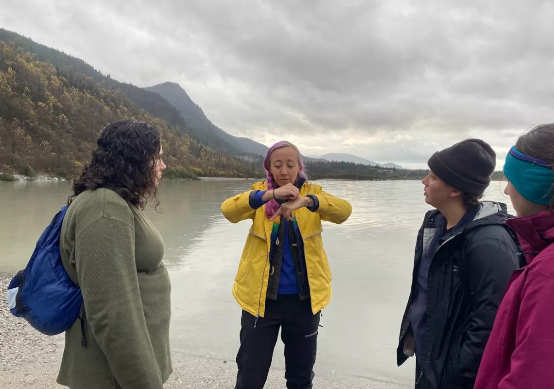 Four people stand in the foreground of a glacier lake