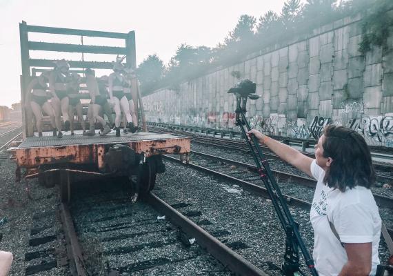 A dance group on a train car, with a photographer capturing their work