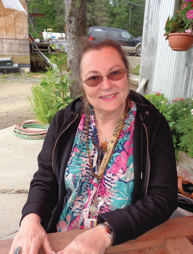 Amy L. Sandridge seated in front of the Wood River Market, smiling and wearing a black jacket.