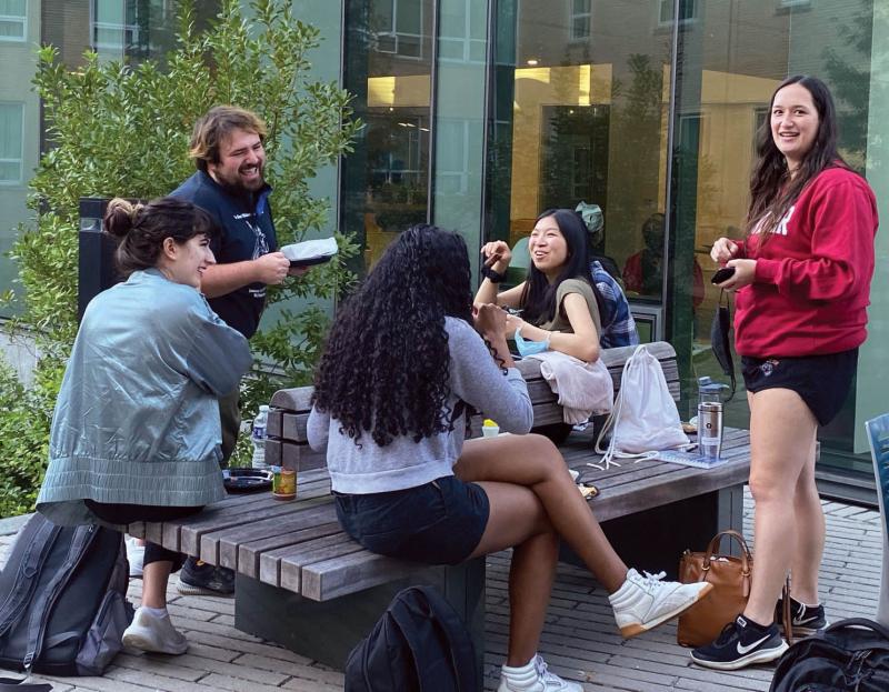 A group of students sit outside talking and laughing