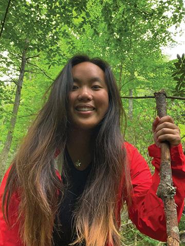 Image of Lili Randolph in the forest with a walking stick.