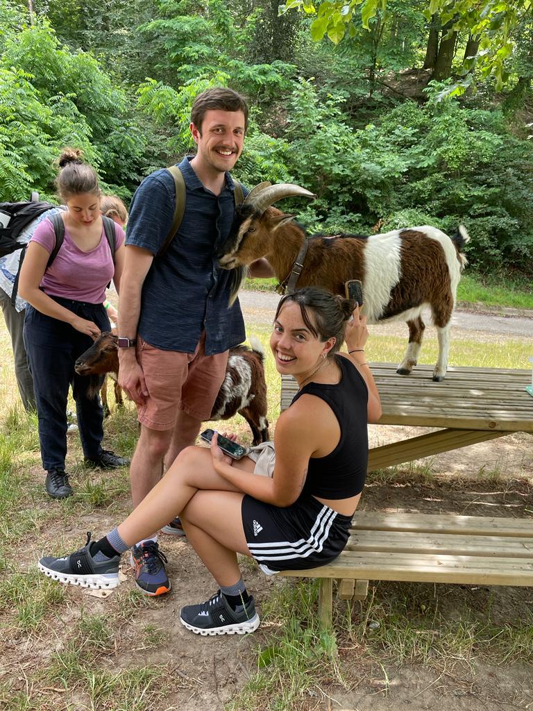 Clara sitting down with goats around. 