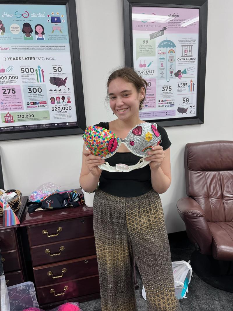 Katie holding a bedazzled bra. 