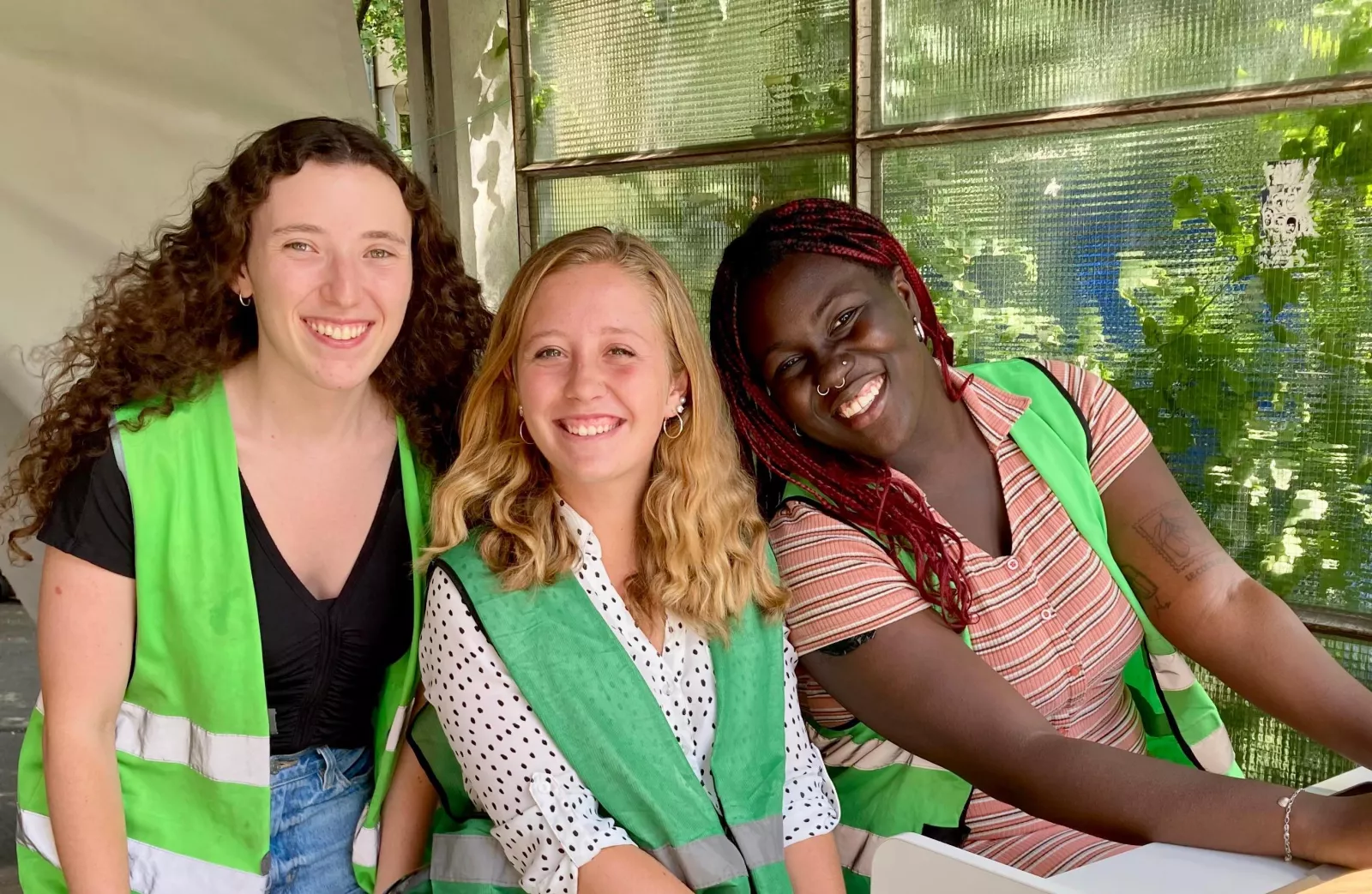 Three people in green vests smiling