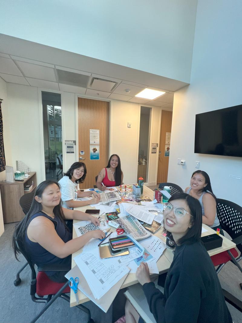 students sitting around a table as they make collages