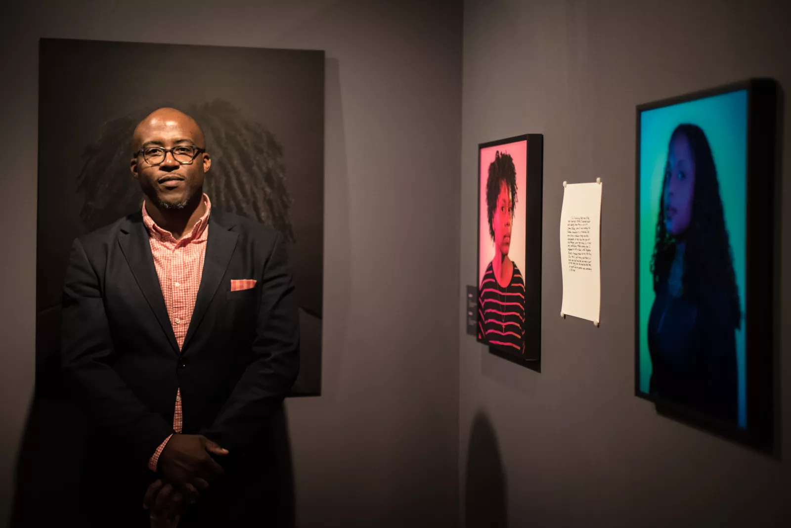 Artist Kris Graves stands in Bryn Mawr's Rare Book Room. Behind him are portraits from the…