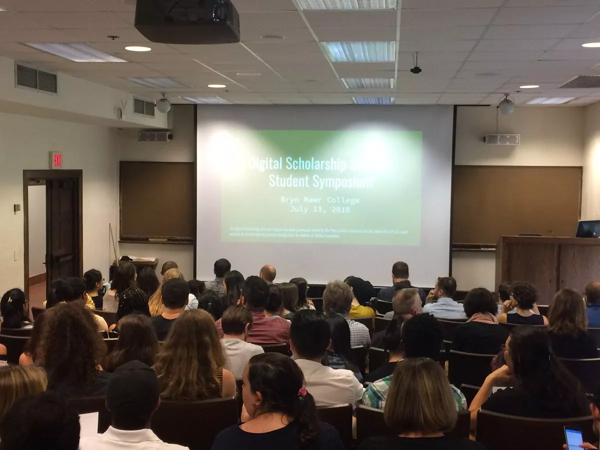 Students gather by a screen at the Symposium kick-off.