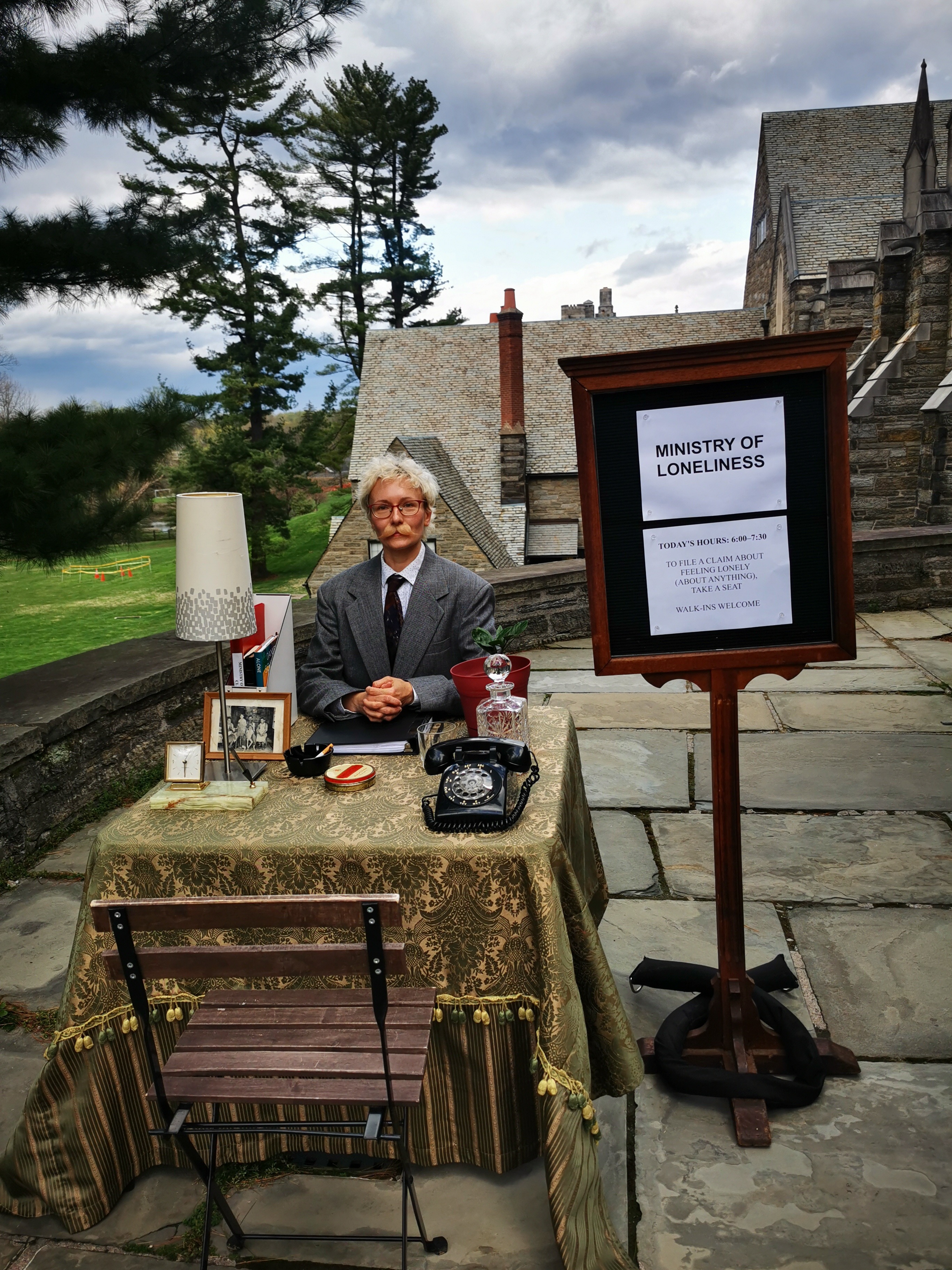 Photo of Minister of Loneliness sitting at a desk on BMC's campus